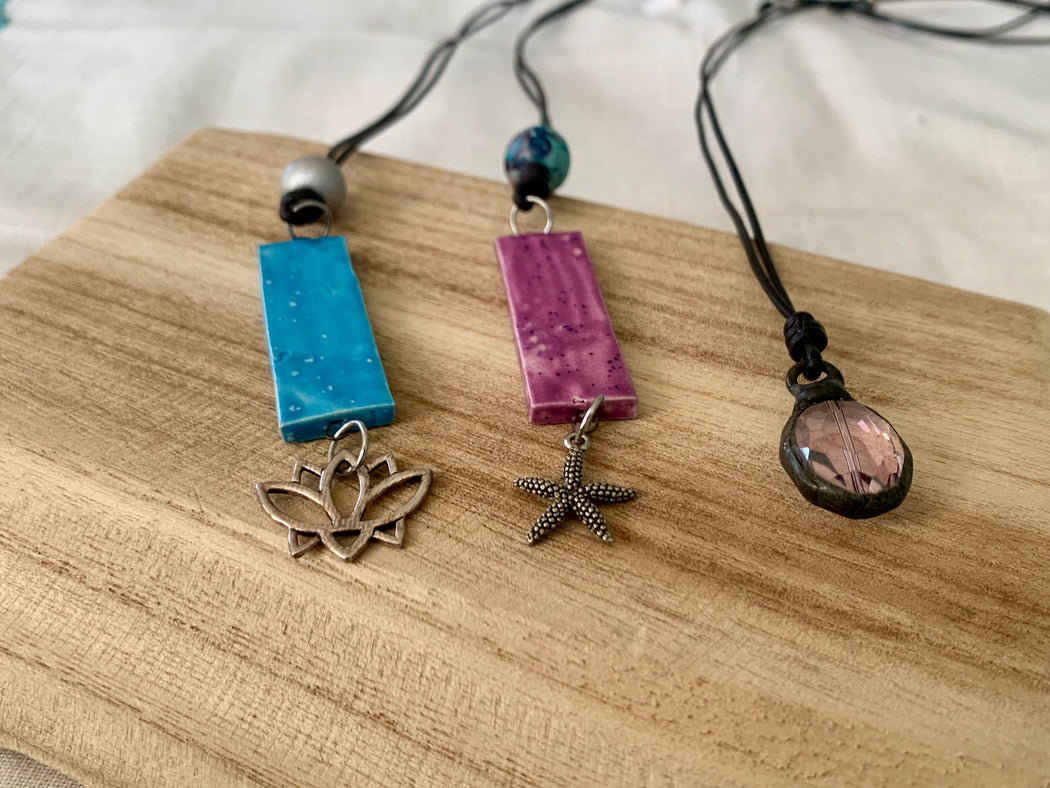 a lotus, starfish or crystal pendant on leather cord.